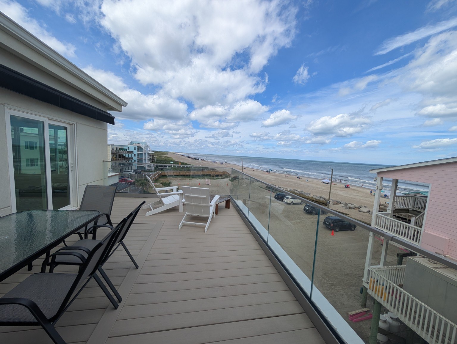 Ocean-view balcony with dining furniture and white chairs at a vacation rental belonging to a client Lisa currently works with